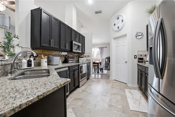 a kitchen with granite countertop a refrigerator stove and sink
