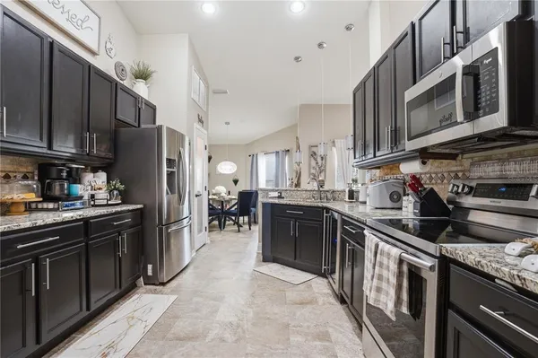 a kitchen with stainless steel appliances granite countertop a stove top oven a sink dishwasher a refrigerator and cabinets with wooden floor