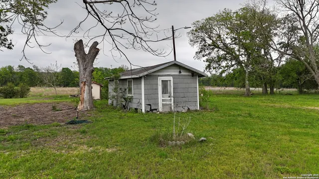 a yellow house with a big yard and large trees