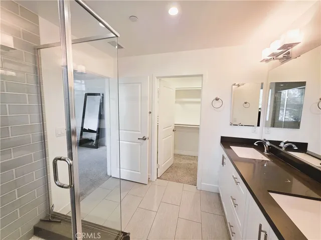 a spacious bathroom with a granite countertop sink a mirror and shower