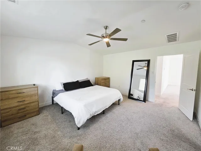 a spacious bedroom with a bed and a ceiling fan
