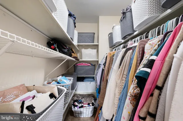 a view of walk in closet with clothes and shoes