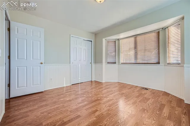 a view of empty room with wooden floor and fan