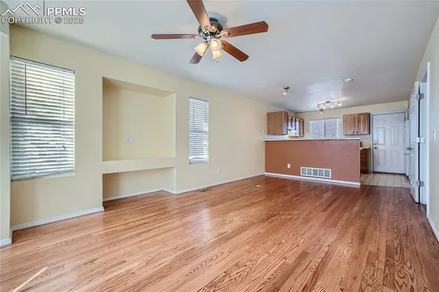 a view of empty room with wooden floor and fan
