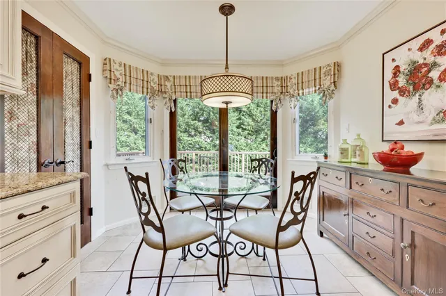 a kitchen with stainless steel appliances granite countertop a stove top oven a sink a dining table and chairs with white cabinets