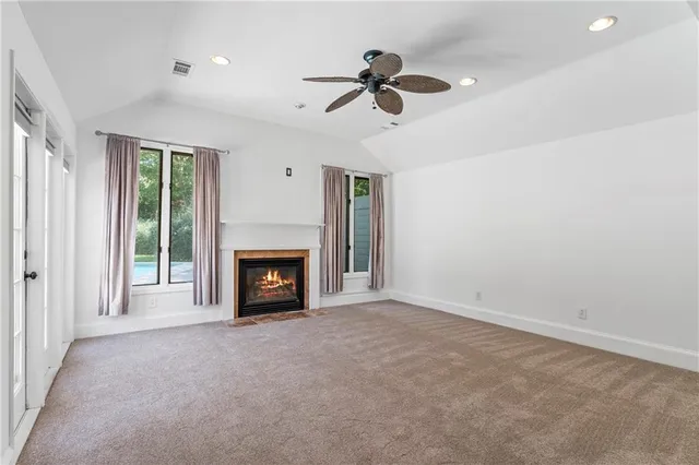 a view of a livingroom with a fireplace a ceiling fan and windows