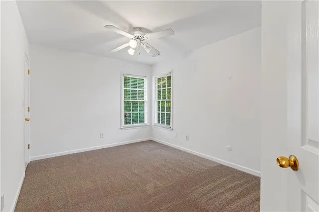 an empty room with windows and chandelier fan