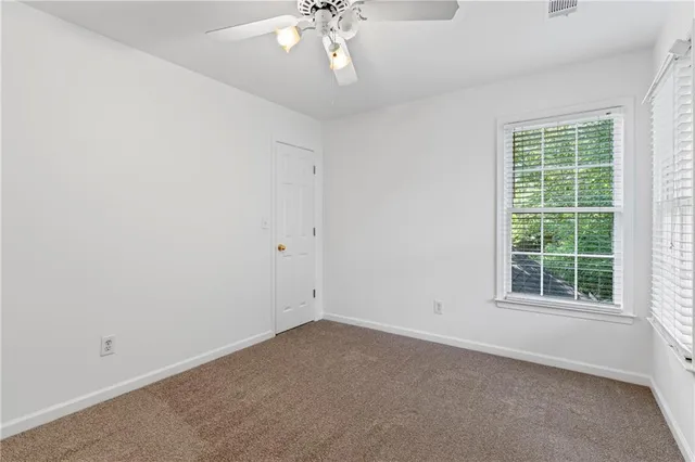 an empty room with a chandelier fan and windows