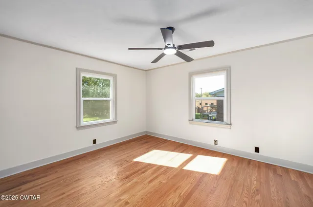 a view of an empty room with a window and wooden floor