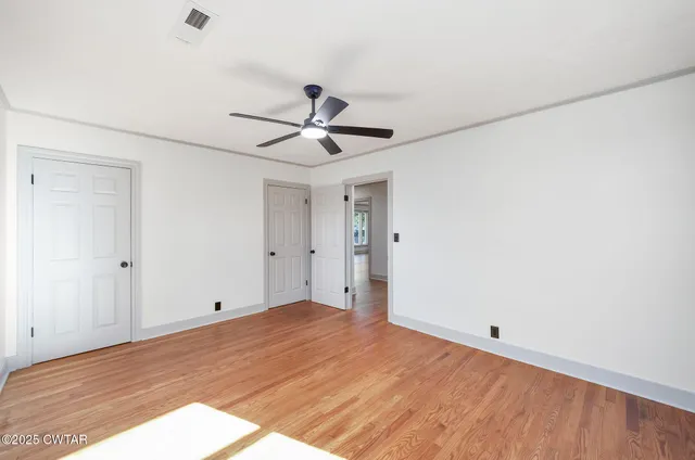 a view of a big room with wooden floor and a ceiling fan
