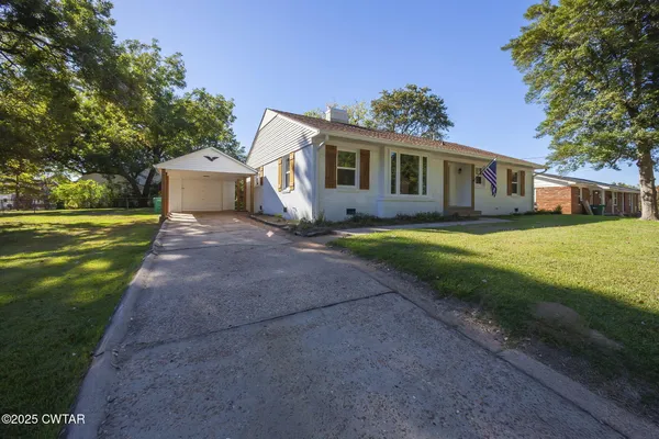 a front view of a house with a yard and trees