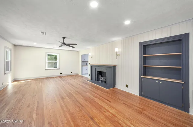 a view of empty room with a fireplace and wooden floor