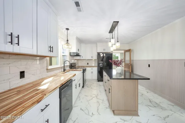a kitchen with stainless steel appliances granite countertop a sink stove and white cabinets