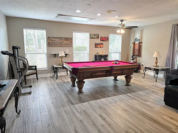 a room with pool table windows wooden floor and front door