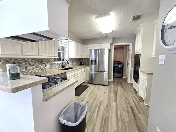 a kitchen with a stove a sink dishwasher a refrigerator and cabinets with wooden floor