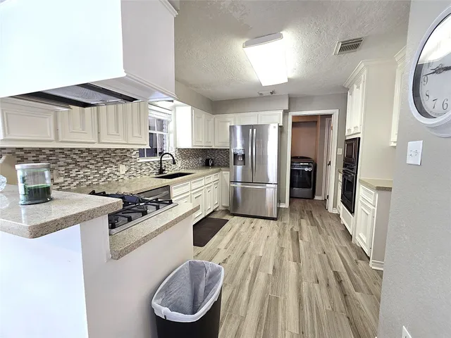 a kitchen with a stove a sink dishwasher a refrigerator and cabinets with wooden floor