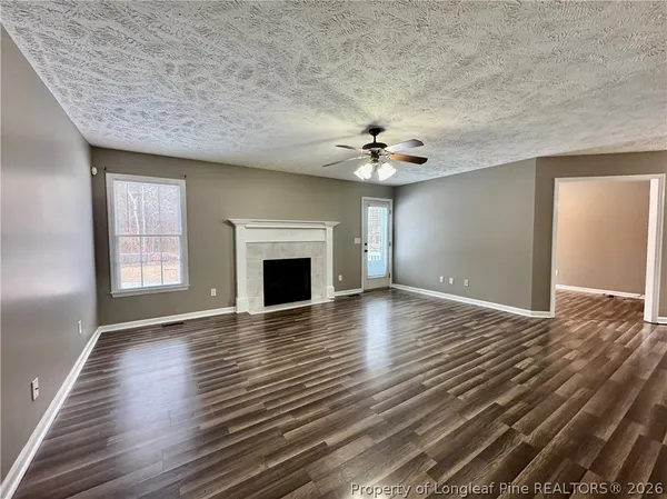 an empty room with chandelier fan and windows
