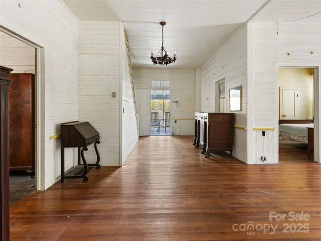 a view of an empty room with wooden floor fireplace and a window