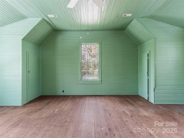 an empty room with wooden floor chandelier fan and windows