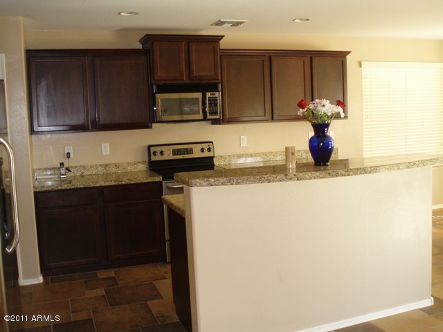 2933 East Blue Sage Road Gilbert, AZ 85297 - Photo 7 of 18 a kitchen with stainless steel appliances granite countertop a refrigerator and a sink