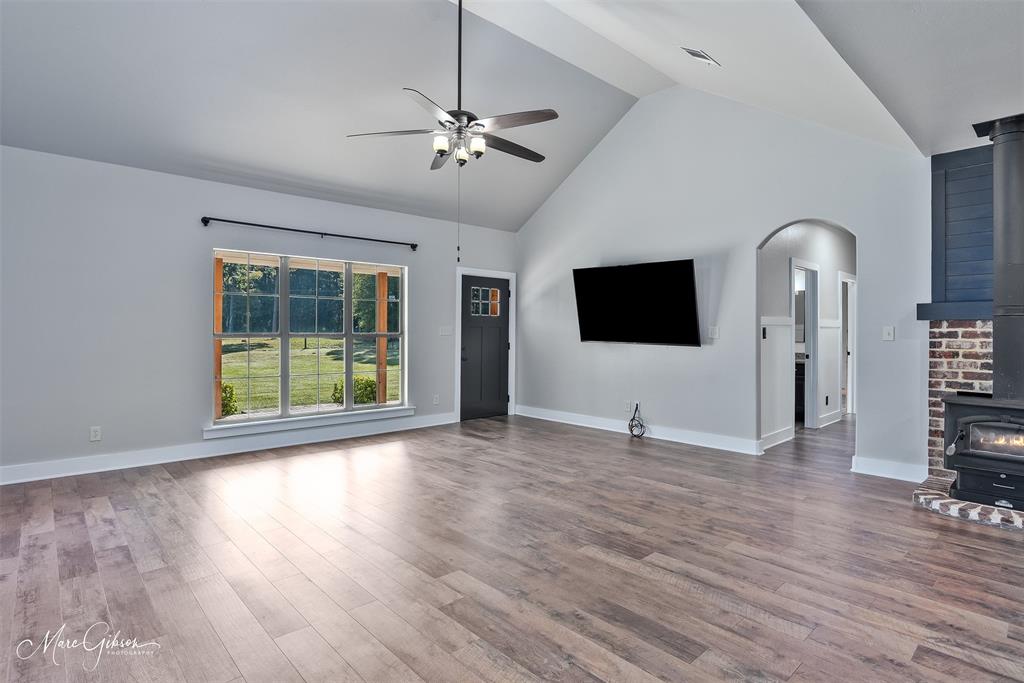550 Linton Bellevue Road Benton, LA 71006 - Photo 10 of 37 Living room with a wood burning stove, high vaulted ceiling, durable wood laminate flooring, a ceiling fan, and arched hallway entry