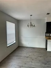 an empty room with chandelier fan and windows