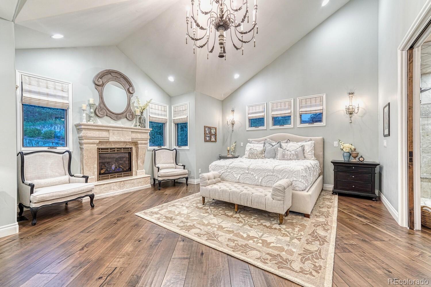 2236 Beechnut Place Castle Rock, CO 80108 - Photo 19 of 40 a bedroom with a bed a fireplace and a chandelier
