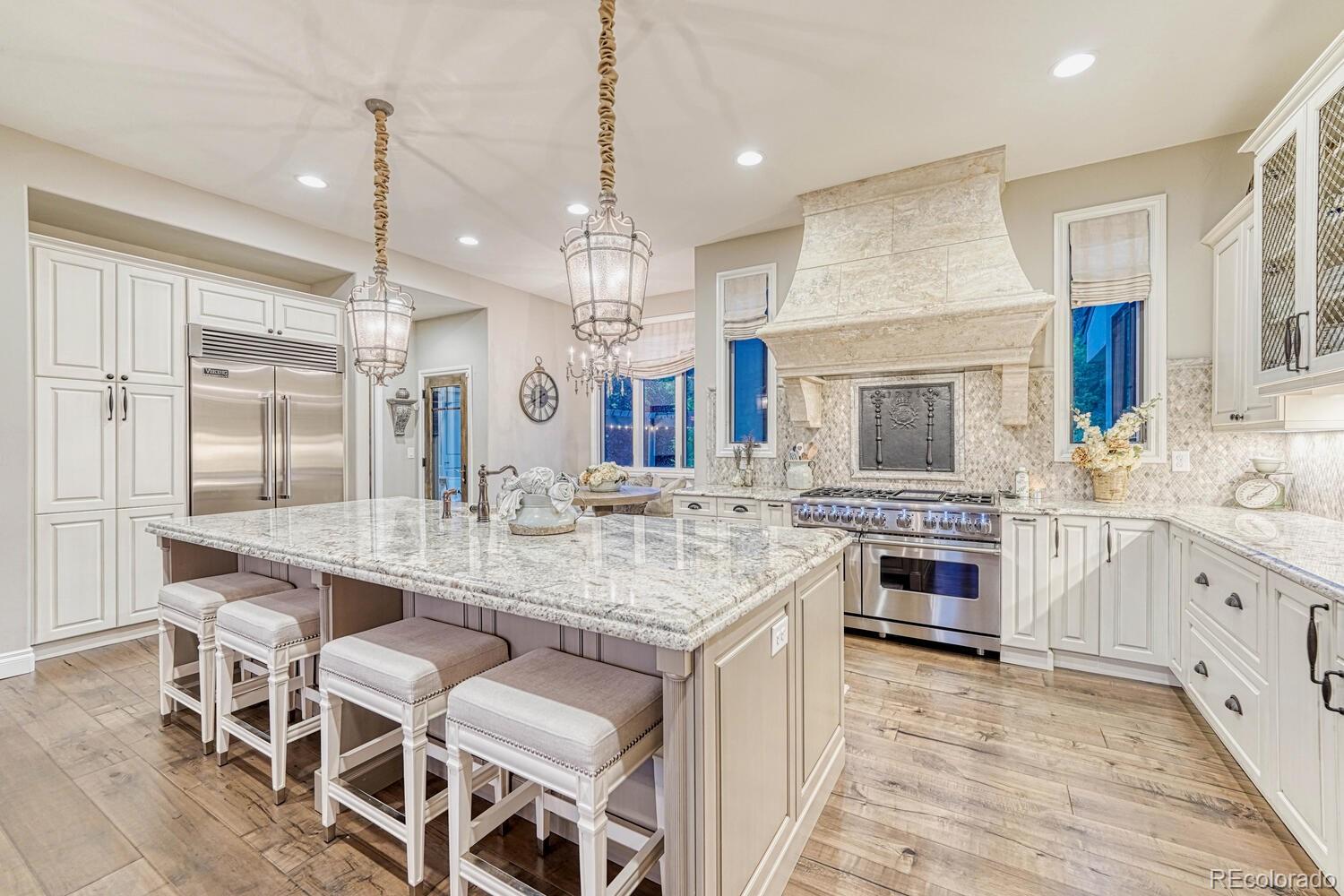 2236 Beechnut Place Castle Rock, CO 80108 - Photo 10 of 40 a large kitchen with kitchen island granite countertop lots of white cabinets a dining table and chairs