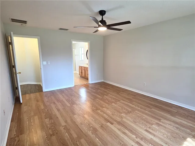 an empty room with wooden floor fan and windows