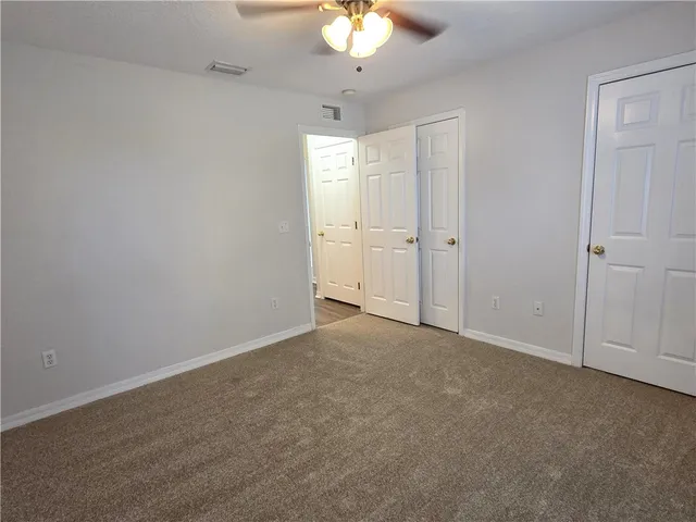 a view of an empty room and a chandelier fan