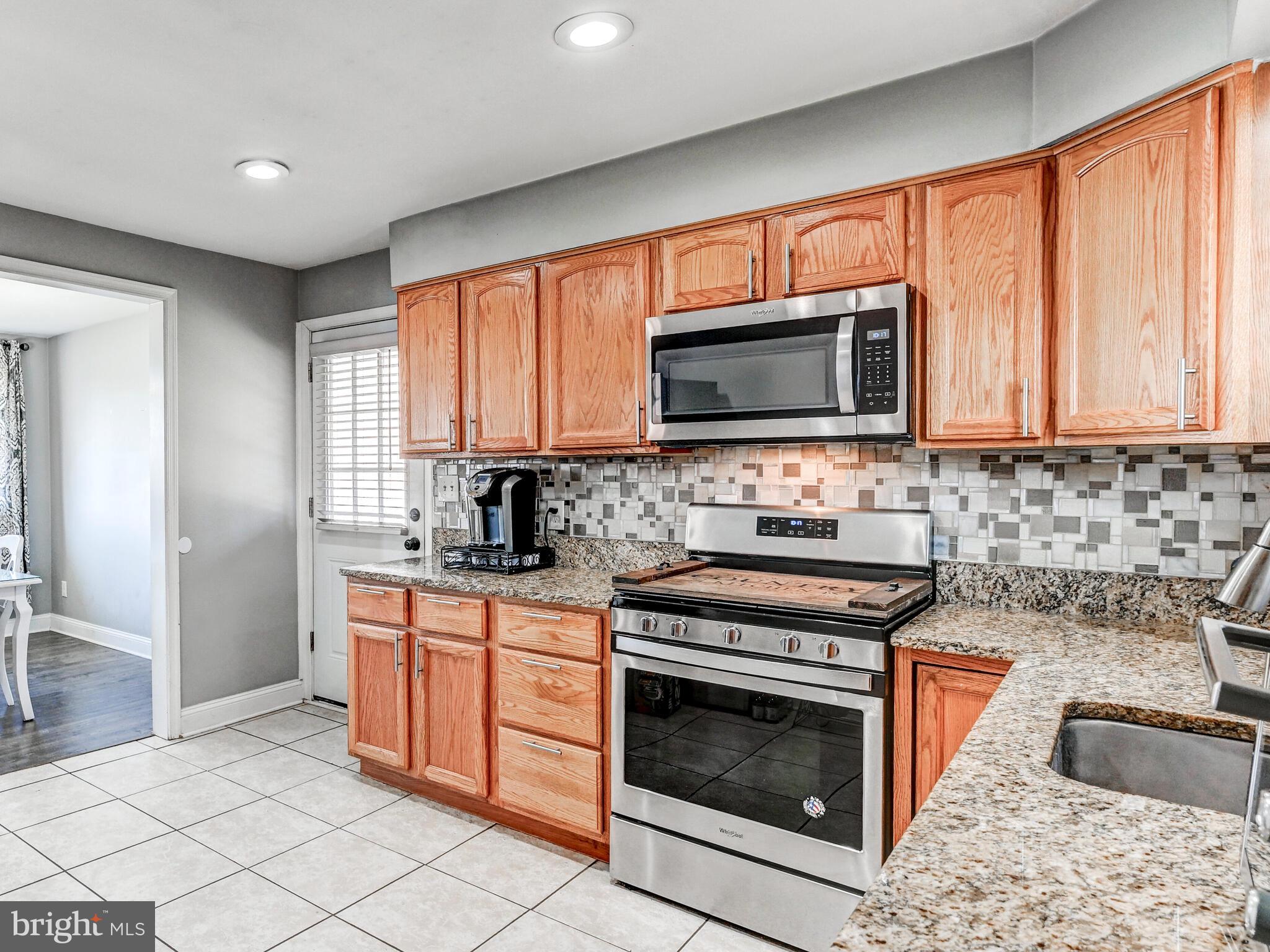 2712 Burridge Road Baltimore, MD 21234 - Photo 17 of 32 a kitchen with granite countertop a stove top oven microwave and cabinets