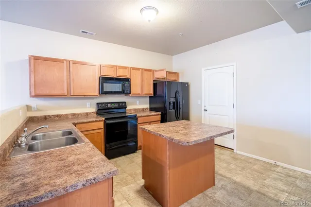 a kitchen with stainless steel appliances granite countertop a stove top oven a refrigerator a sink and a microwave