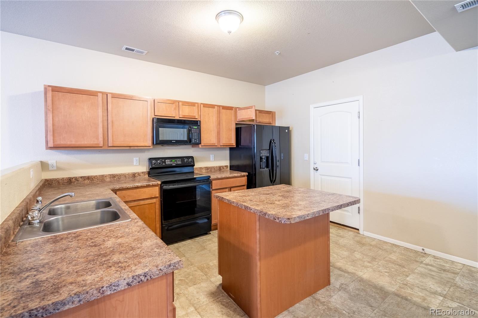 4910 Pearl Kite View Colorado Springs, CO 80916 - Photo 5 of 16 a kitchen with granite countertop a sink a stove and a refrigerator