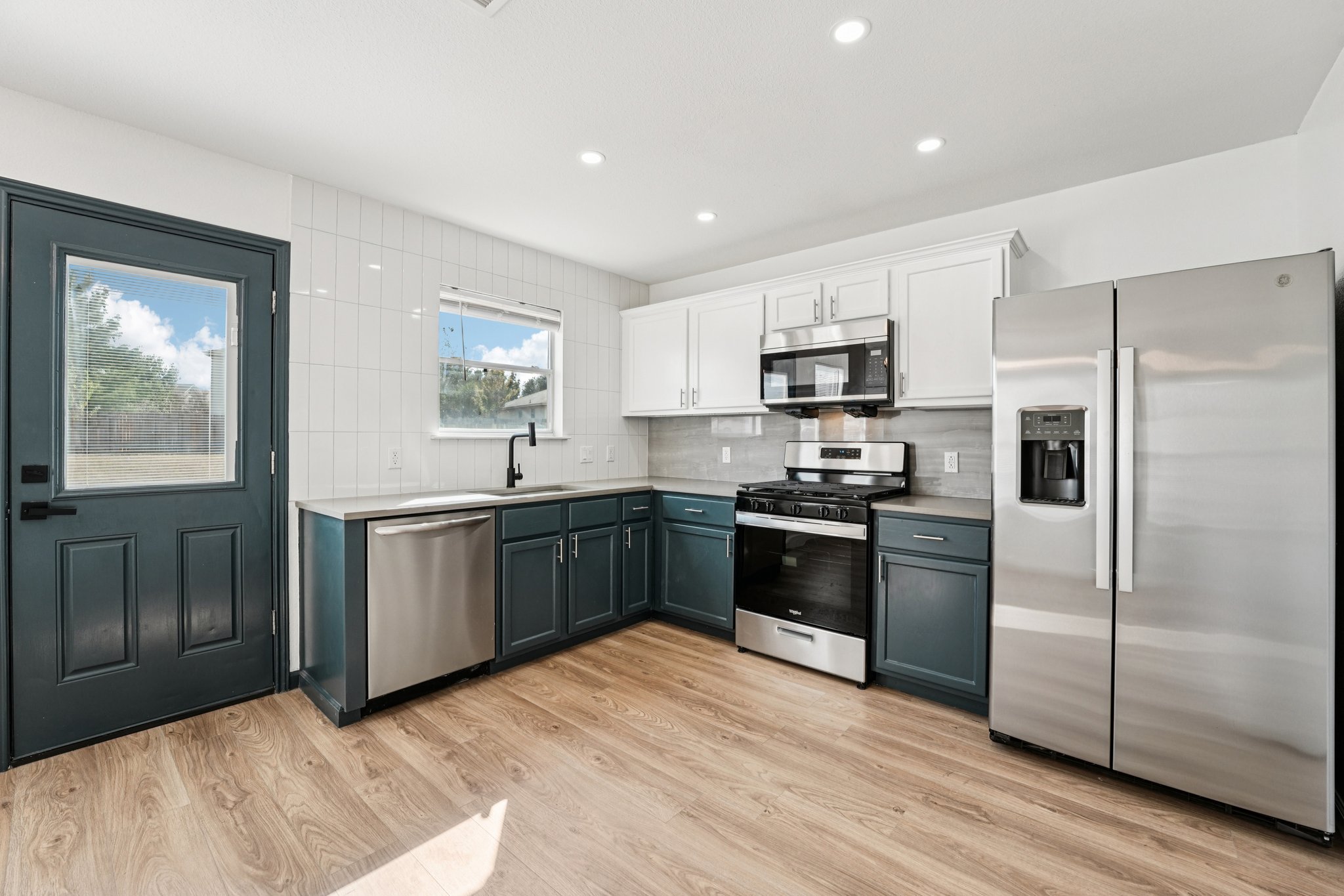 a kitchen with granite countertop a refrigerator stove top oven and sink