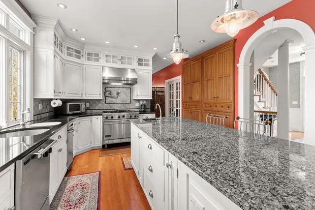 a kitchen with stainless steel appliances granite countertop a sink a stove and a wooden floors