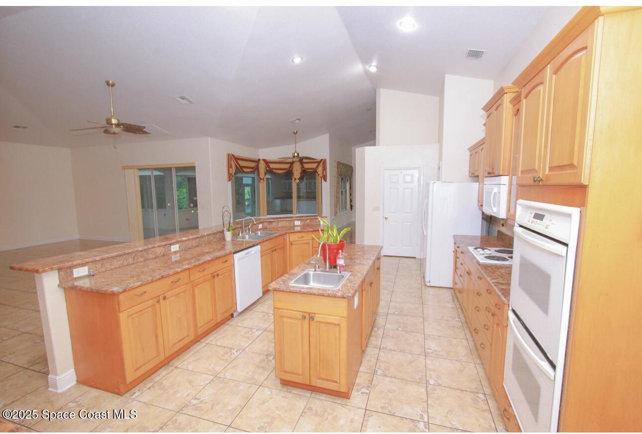1857 Timbers W Boulevard Rockledge, FL 32955 - Photo 15 of 44 a large kitchen with stainless steel appliances kitchen island granite countertop a refrigerator and a stove