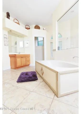 a spacious bathroom with a tub sink and mirror