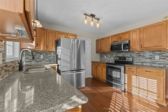 a kitchen with stainless steel appliances granite countertop a refrigerator a stove a sink and dishwasher
