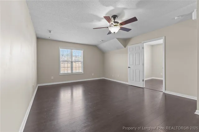 an empty room with wooden floor and ceiling fan