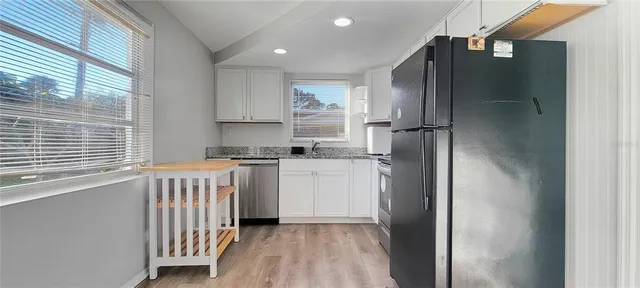 a kitchen with a refrigerator and white cabinets