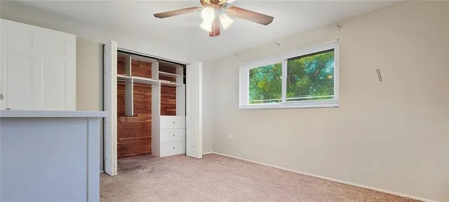an empty room with windows closet and chandelier fan