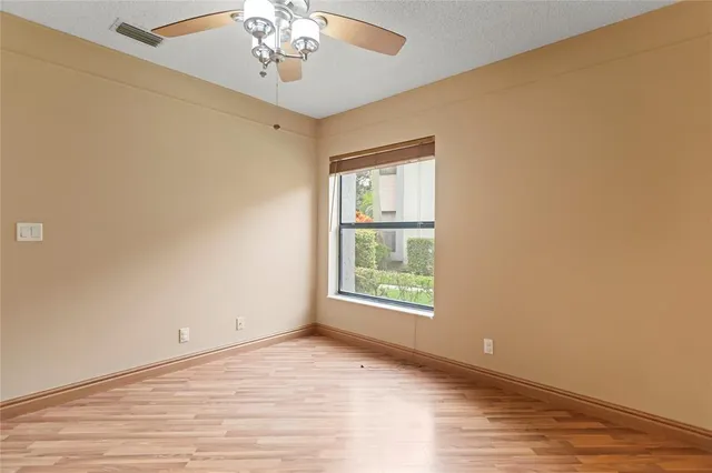 a view of an empty room with a window and wooden floor