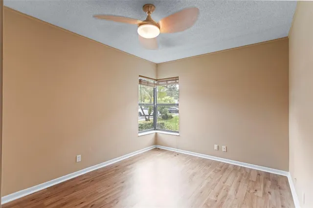 an empty room with a window and ceiling fan