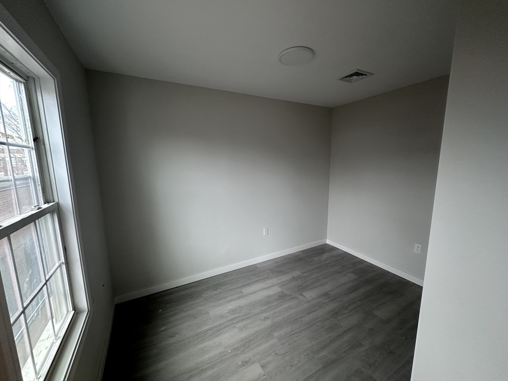 18 Marlborough Street, Unit 2L Chelsea, MA 02150 - Photo 3 of 7 an empty room with wooden floor and windows