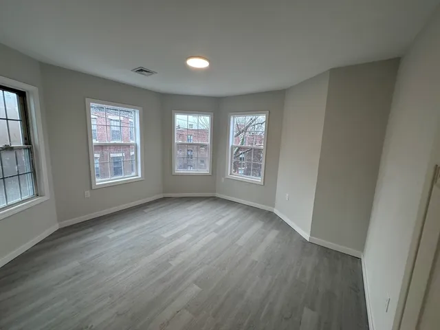 a view of an empty room with wooden floor and windows
