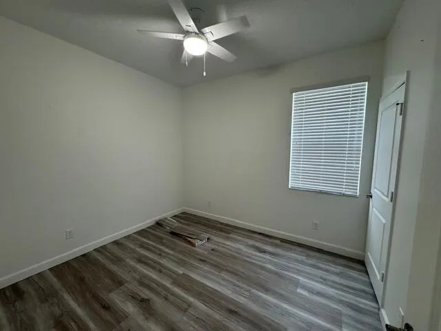 an empty room with a window and ceiling fan