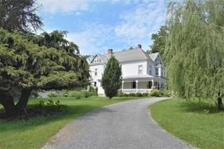 a view of house with a big yard and large trees