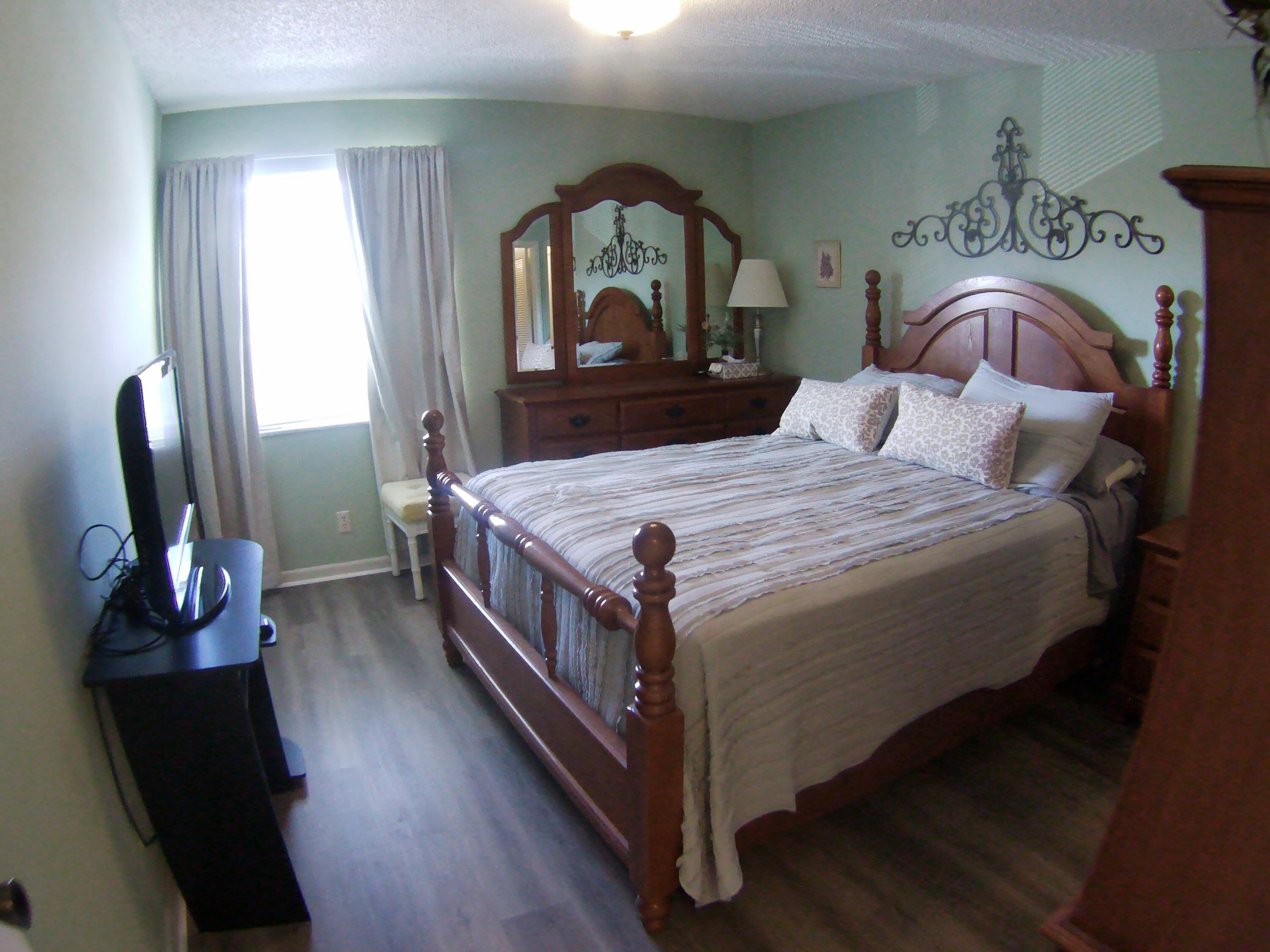 571 Capri L Delray Beach, FL 33484 - Photo 27 of 33 a bedroom with a bed a mirror on dresser and a wooden floor