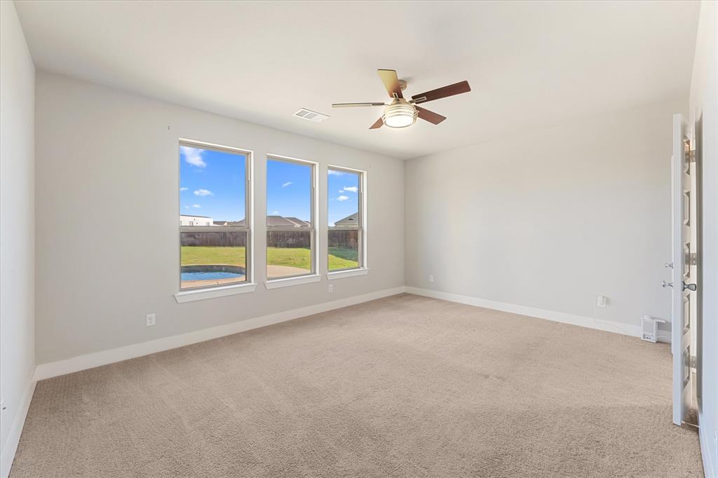 2044 Longbridge Road Forney, TX 75126 - Photo 13 of 40 Spacious room featuring three large windows, neutral carpet flooring, a ceiling fan with light, and light-colored walls