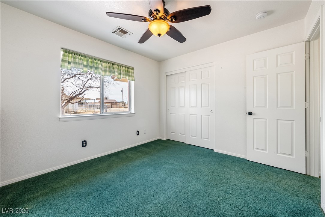 3581 Ranger Way Pahrump, NV 89048 - Photo 27 of 57 2nd bedroom featuring dark colored carpet, a closet, visible vents, a ceiling fan, and baseboards